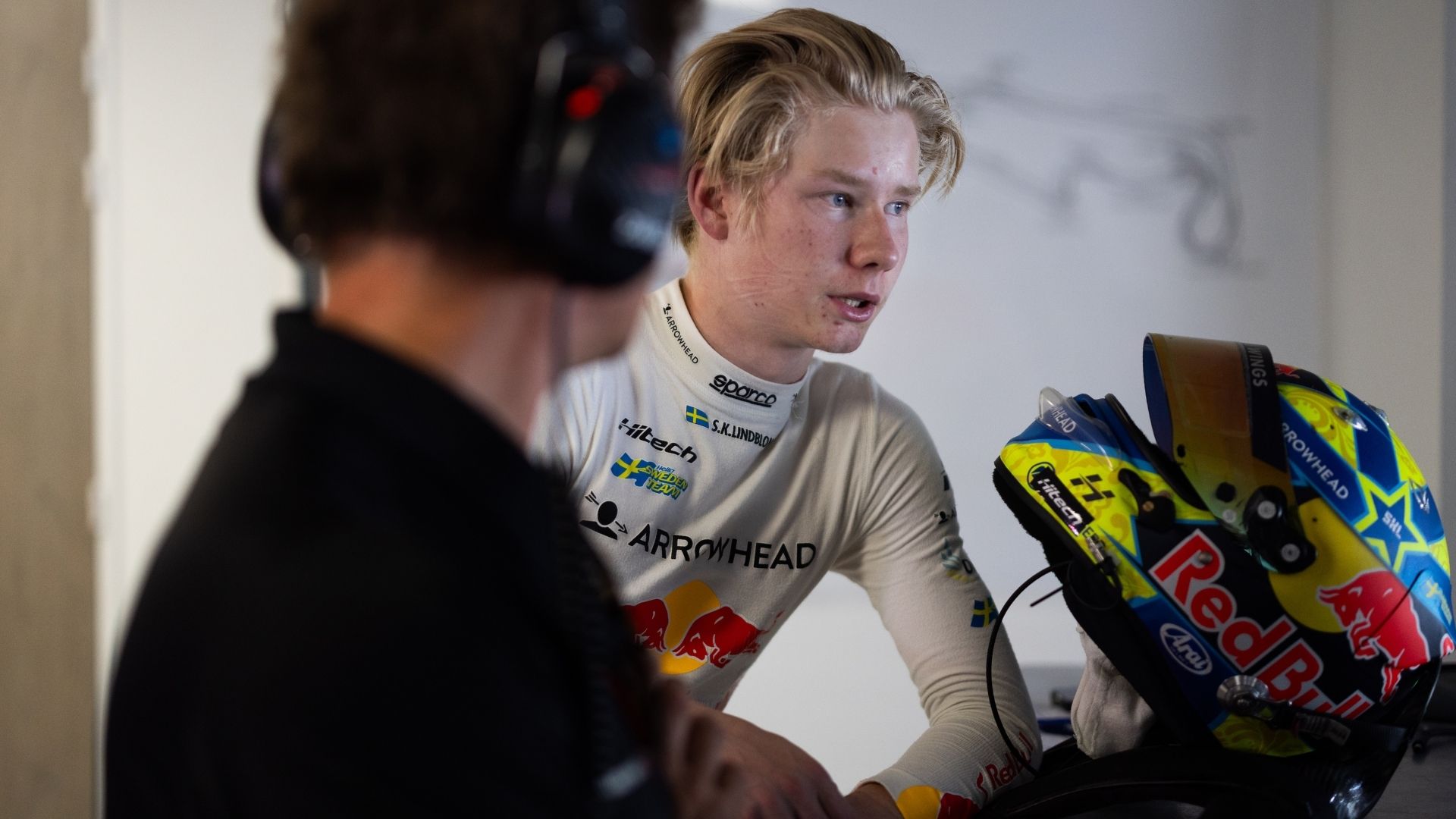 Scott Kin Lindblom i samtal med en ingenjör i depån, med Red Bull-hjälmen i förgrunden
