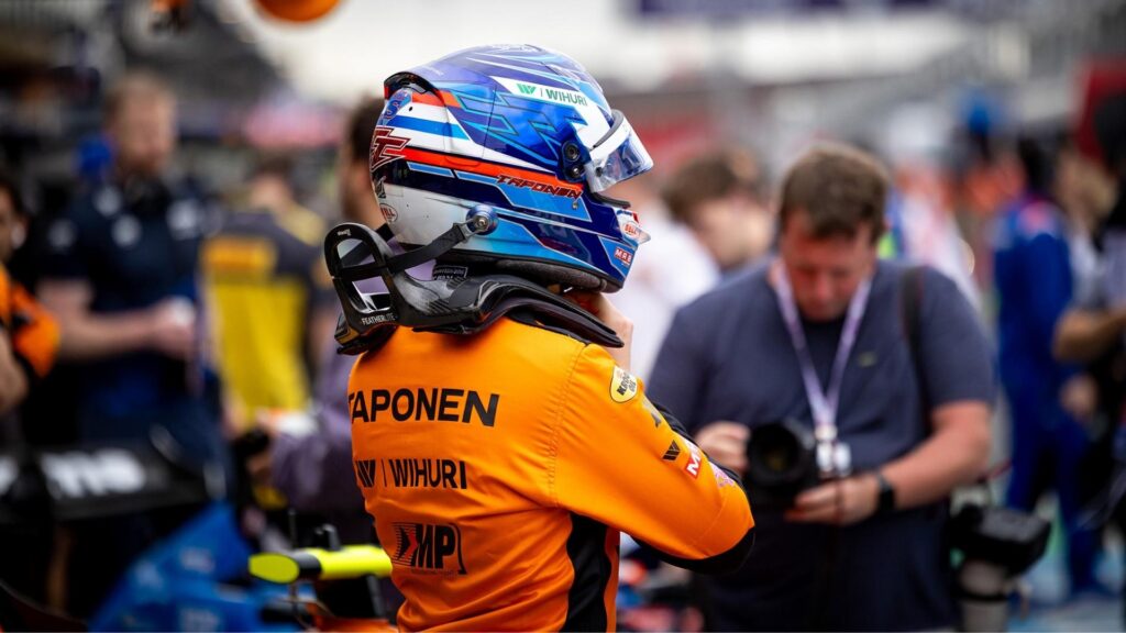 Tuukka Taponen i orange MP Motorsport-overall justerar sin blåvita hjälm i depån